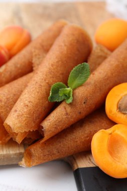 Lezzetli meyve dürümleri ve kayısılar beyaz ahşap masada, yakın plan