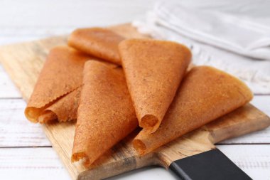 Lezzetli meyve derisi beyaz ahşap masada yuvarlanıyor, yakın plan.