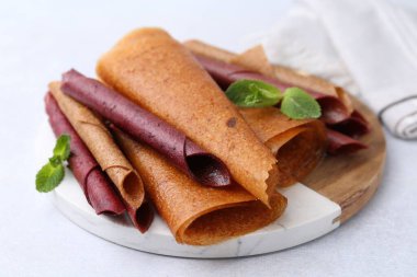 Lezzetli meyve ruloları ve nane şekeri ışık masasında, yakın plan.