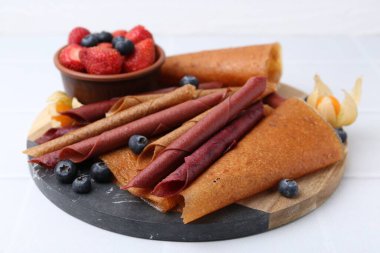 Lezzetli meyve dürümleri ve beyaz masada meyveler, yakın plan.