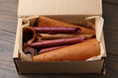 Lezzetli meyve ruloları karton kutunun içinde ahşap masanın üstünde, manzaranın üstünde.