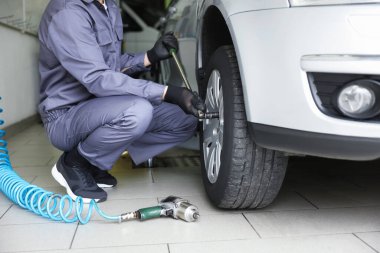 Tamirci araba servisinde lastik değiştiriyor, yakın plan.