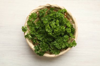 Açık ahşap masada, sepetin içinde taze maydanoz.