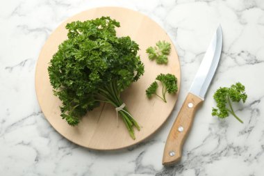 Bir demet taze maydanoz ve bıçak beyaz mermer masada, düz yatıyordu.