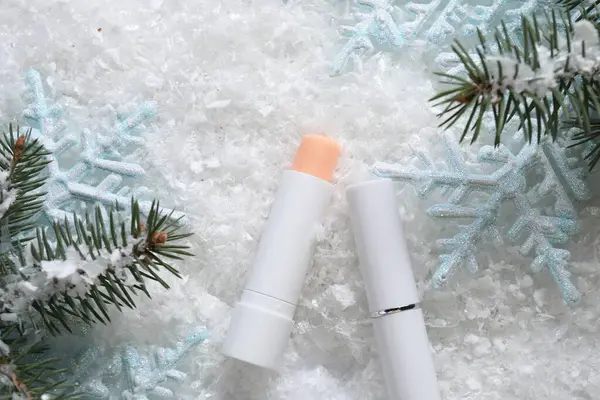 Nemlendirici dudak kremleri, Noel dekorasyonu ve yapay kar üzerindeki köknar ağacı dalları. Kış bakımı