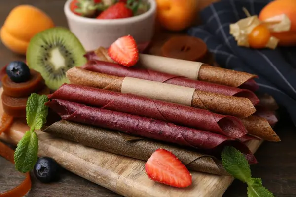 Lezzetli deri rulo şekerler, ahşap masada meyveler, yakın plan.