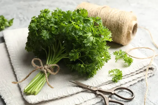 Taze maydanoz, iplik ve makas gri desenli masa, yakın plan.