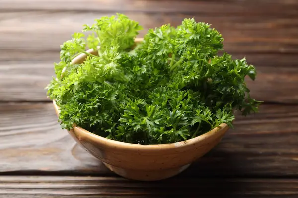 Tahta masadaki kasede taze kıvırcık maydanoz, yakın plan.