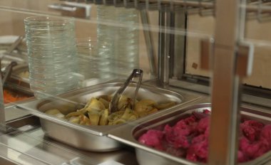 Okul kantininde içinde lezzetli yemekler olan konteynırlar.