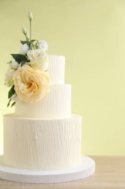 Ahşap masada çiçeklerle süslenmiş nefis bir düğün pastası açık yeşil arka planda, yakın plan.