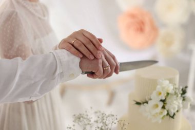 Evli çift içeride bıçakla lezzetli bir düğün pastası kesiyor.