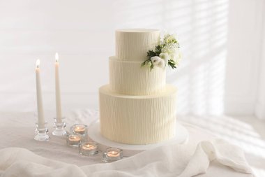 Çiçek desenli nefis düğün pastası ve içeride yanan mumlar.