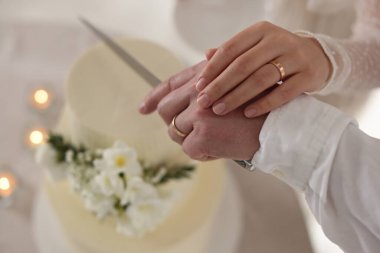 Evli çift içeride bıçakla lezzetli bir düğün pastası kesiyor.