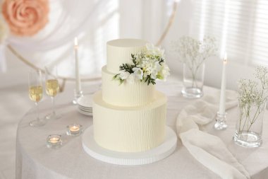 Çiçek desenli nefis düğün pastası ve kapalı bir masada şampanya bardakları.