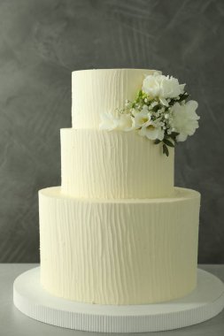 Gri arka planda çiçek dekoru olan nefis düğün pastası.