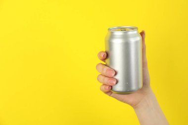 Sarı arka planda teneke kutusu olan kadın, yakın plan. Metin için boşluk