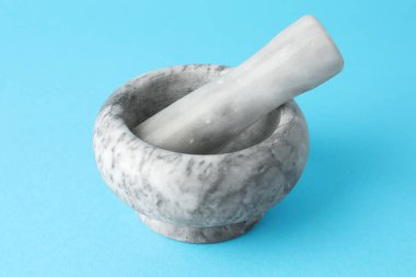 Açık mavi arkaplanda mermer harç ve tokmak, yakın plan