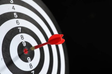 Hedef alınıyor. Siyah arka planda ok olan dart tahtası, yakın plan. Metin için boşluk