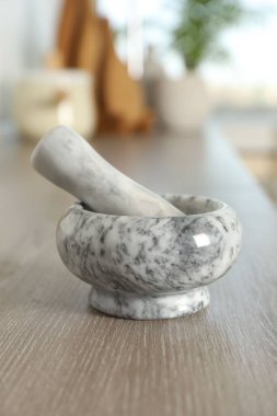 Mutfaktaki ahşap masada mermer harç ve tokmak, yakın plan.