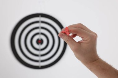 Hedef alınıyor. Oklu bir adam arka planda dart tahtasına nişan alıyor, yakın plan.