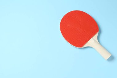 Açık mavi arka planda bir pinpon raketi, üst manzara. Metin için boşluk