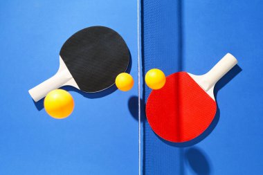 Masa tenisi raketleri, toplar ve ağ mavi arka planda, düz yatıyordu.