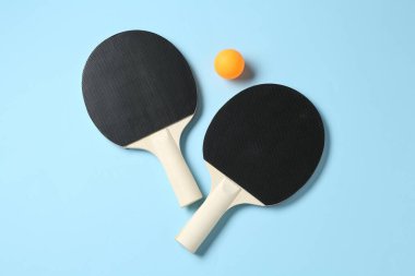 Masa tenisi raketleri ve top açık mavi arka planda, düz yatıyordu.
