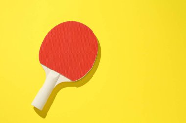 Sarı arka planda bir pinpon raketi, üst manzara. Metin için boşluk