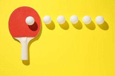 Masa tenisi raketi ve toplar sarı arka planda, düz yatıyordu