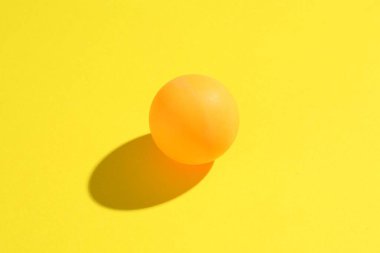 Sarı arka planda bir ping pong topu, yakın plan.