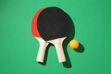 Yeşil zemin üzerinde pinpon raketleri ve top düz yatıyordu.