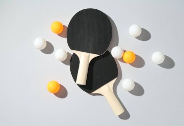 Masa tenisi raketleri ve topları arka planda, düz yatıyordu.