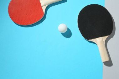 Renkli arka planda pinpon raketleri ve top, üst görünüm. Metin için boşluk