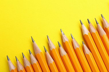 Sarı arka planda keskin grafit kalemler, düz. Metin için boşluk