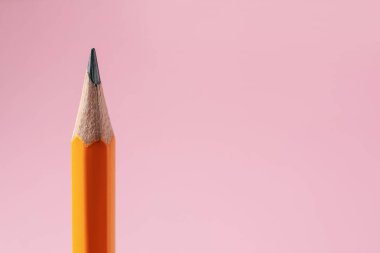 Pembe arka planda keskin bir grafit kalem, yakın plan. Metin için boşluk