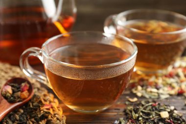 Bitki çayı ve kuru yaprakları ahşap masaya serpmek, yakın plan.