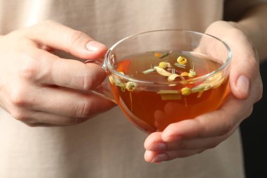 Cam bardakta aromalı bitkisel çayı olan kadın, yakın plan.
