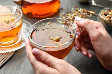 Siyah masada aromatik bitki çayı olan kadın, yakın plan.