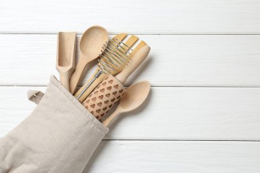 Fırın eldivenindeki farklı mutfak aletleri beyaz ahşap masa, üst manzara. Metin için boşluk