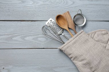 Fırın eldivenindeki farklı mutfak aletleri açık gri ahşap masa, üst manzara. Metin için boşluk