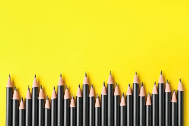 Sarı arka planda bir sürü keskin grafit kalem, düz bir zemin. Metin için boşluk