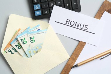 Açık gri zemin üzerinde kelime bonusu, para, pano ve hesap makinesi olan kart, düz yatıyordu