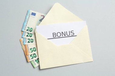 Açık gri arka planda para ve kelime bonusu içeren zarf, üst görünüm