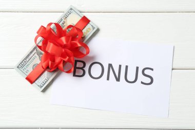 Para bonusu. Beyaz ahşap masa üzerinde fiyonklu ve kartlı banknotlar, düz yatıyordu.