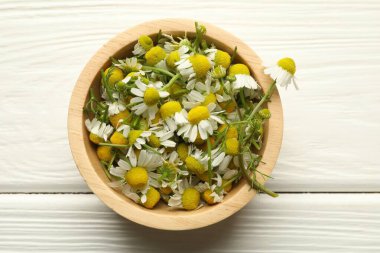 Beyaz ahşap masada kasede taze papatya çiçekleri.