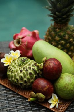 Yüzme havuzu yakınındaki hasır masada farklı bir tropikal meyve.