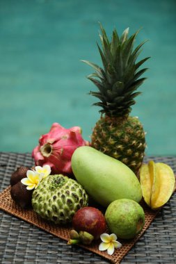 Yüzme havuzu yakınındaki hasır masada farklı bir tropik meyve.