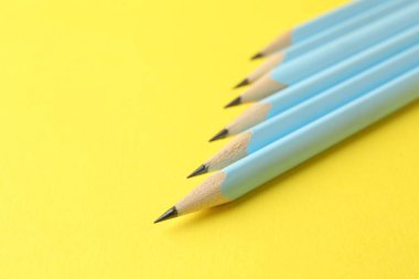 Many graphite pencils on yellow background, closeup. Space for text