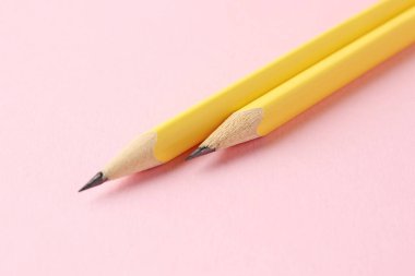 Pembe arka planda iki grafit kalem, yakın plan.