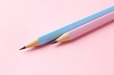 Pembe arka planda iki grafit kalem, yakın plan.